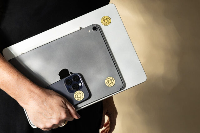 Harmoni MF Protections stickers on table, laptop, and cellphone.