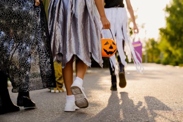 Children in Halloween costumes walking down street during trick-or-treating outdoors