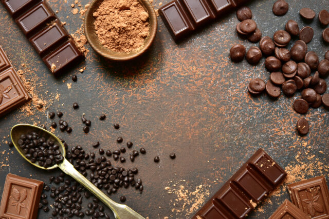 Ingredients for making chocolate cake or candy : chocolate chips, bar and spices on a dark slate, stone or concrete background.Top view with copy space.