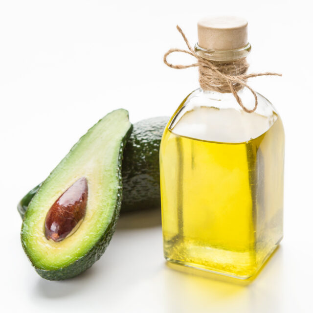 Avocado and oil in bottle on white background. Natural skin care concept